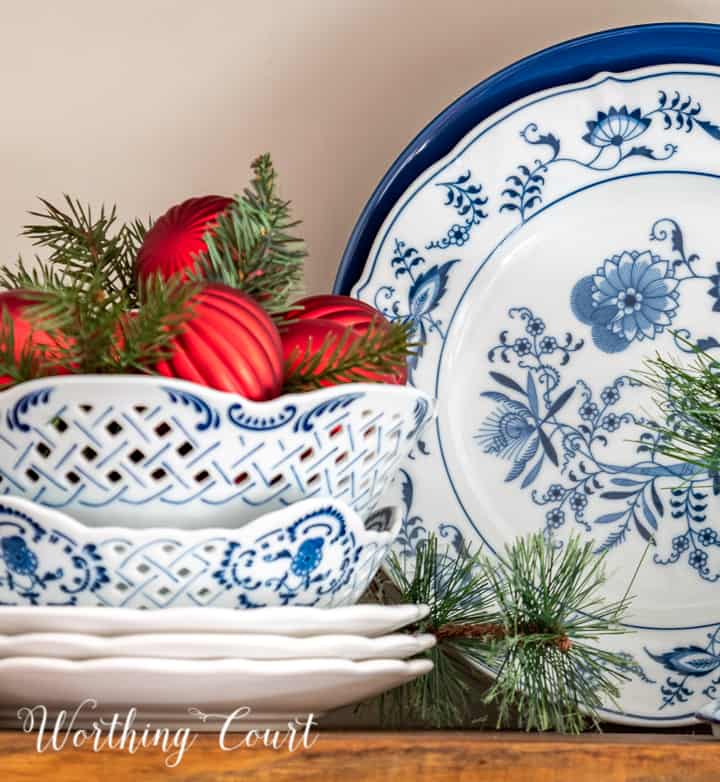 blue and white dishes on a shelve with red Christmas ornaments in bowl