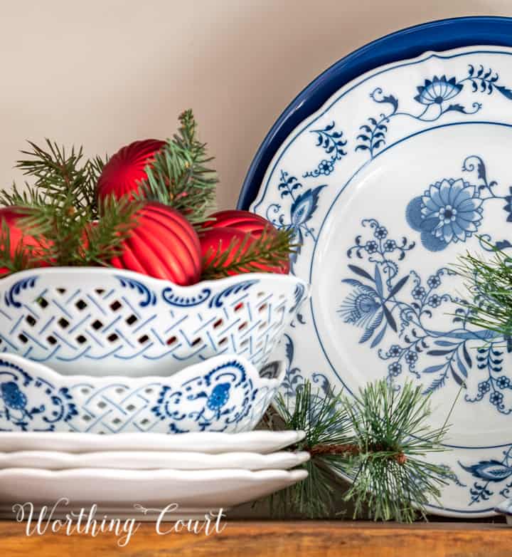 blue and white dishes on a shelve with red Christmas ornaments in bowl