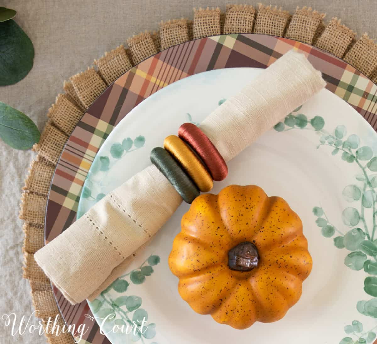 portion of thanksgiving tablescape with fall colors and eucalyptus in the centerpiece