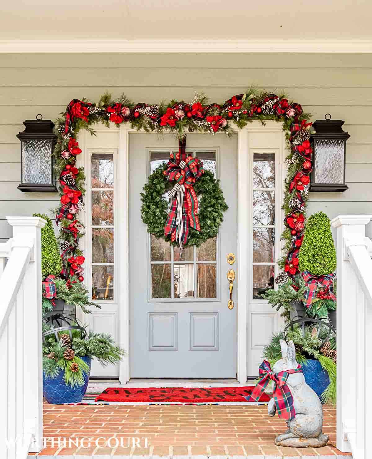 Front porch decorated for Christmas with red and green decorations