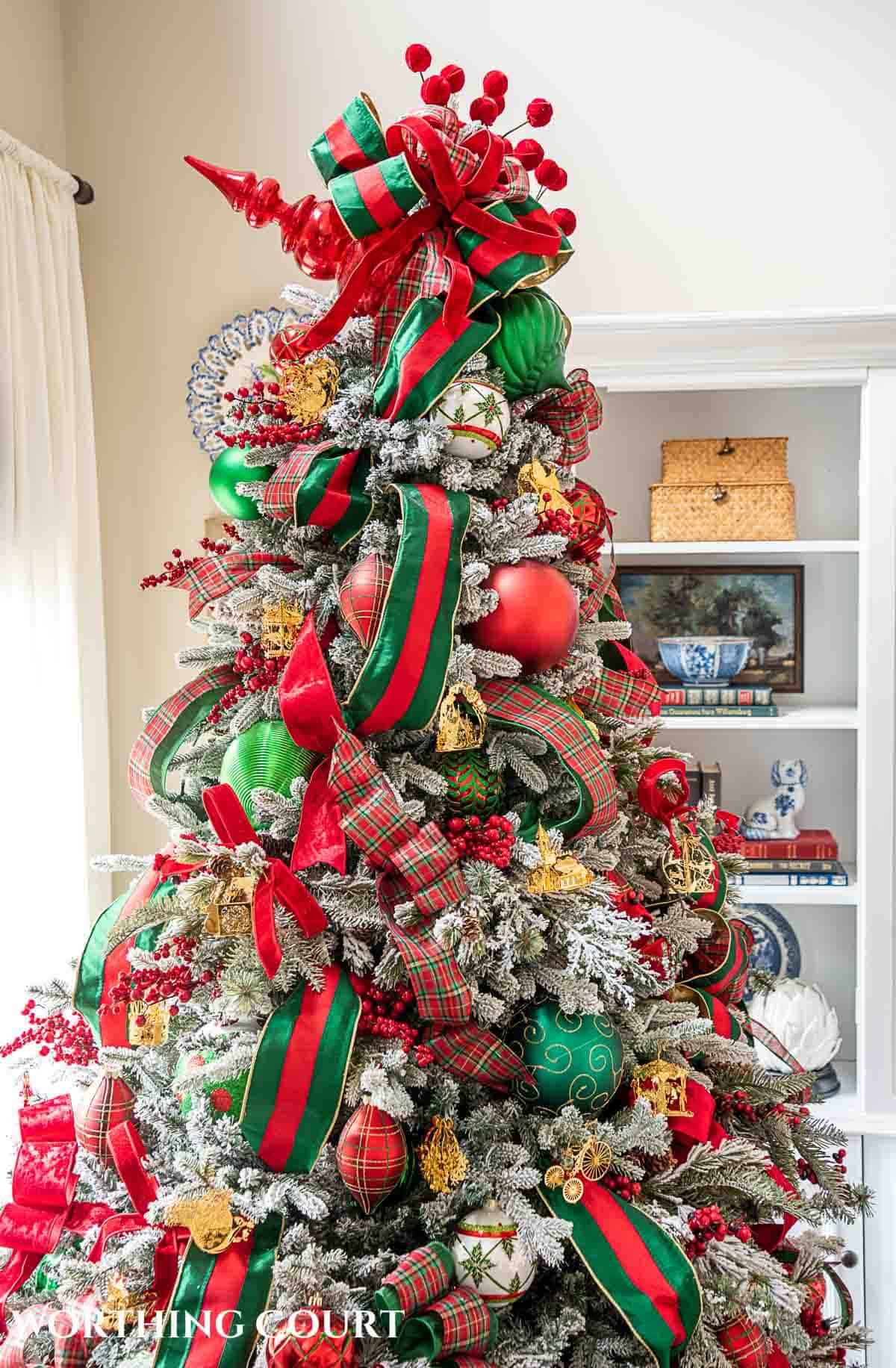 Christmas tree, fireplace and living room decorated for Christmas with red green and gold decorations