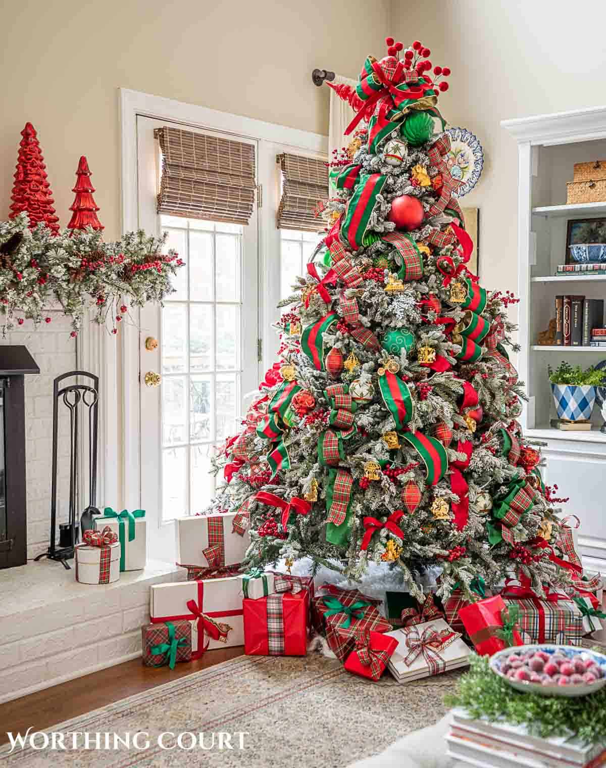 Christmas tree, fireplace and living room decorated for Christmas with red green and gold decorations