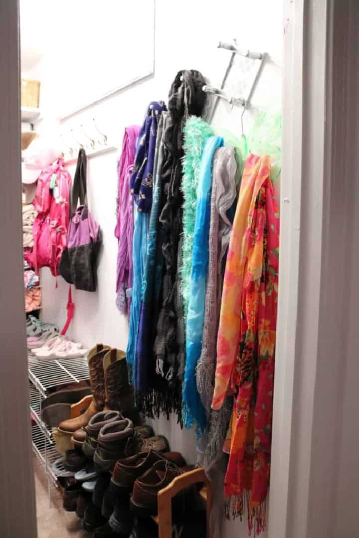 scarves and purses hanging from hooks in a small closet