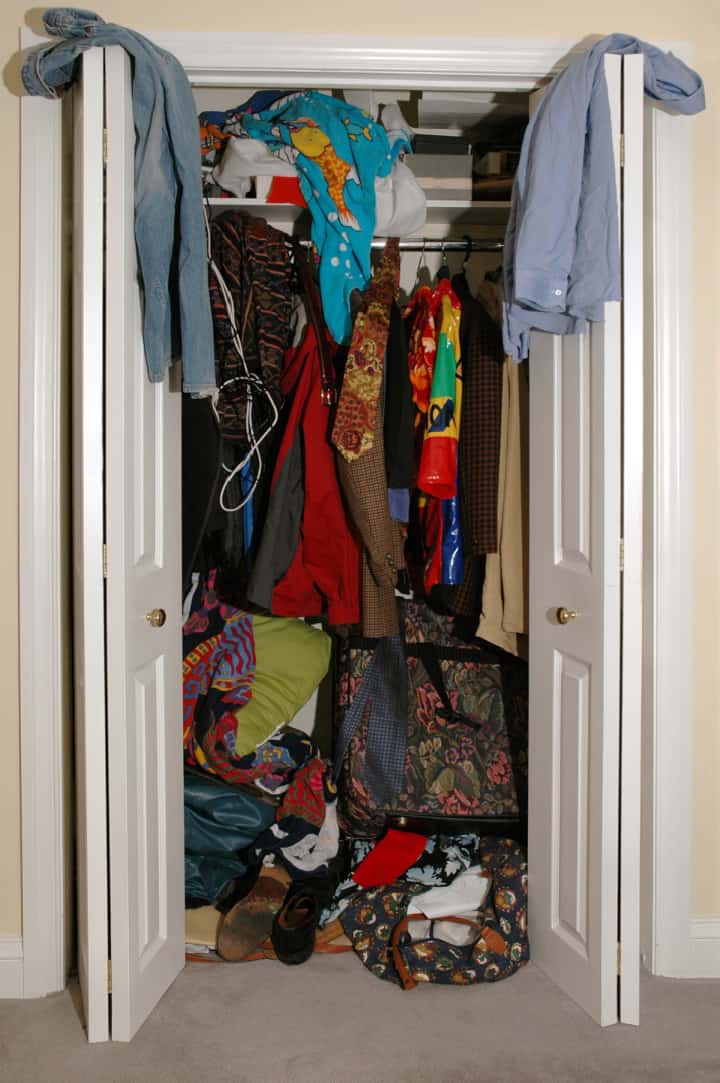 small closet with messy clothing that needs to be organized