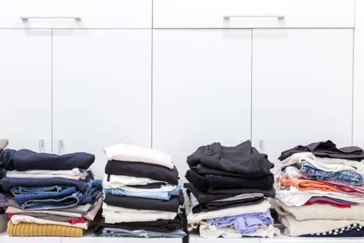 stacks of folded clothes ready to be organized in a closet