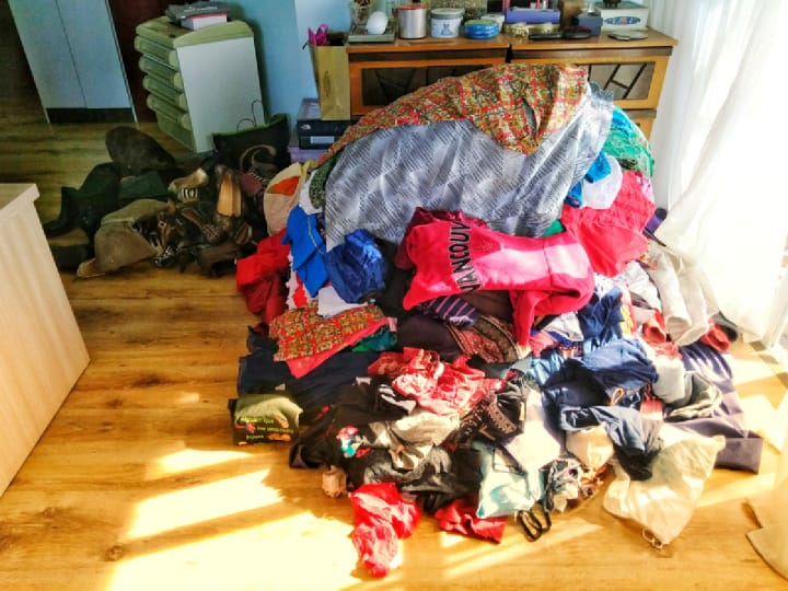 pile of clothes on the floor to sort through before organizing a closet