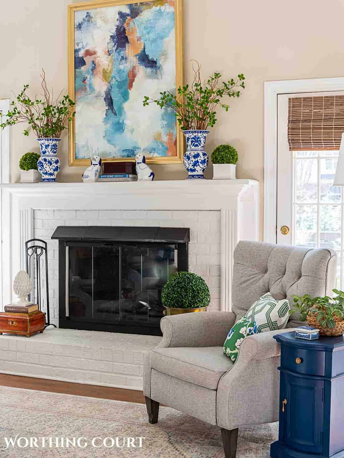 living room spring decorations with greenery stems in blue and white vases on a white brick fireplace mantel