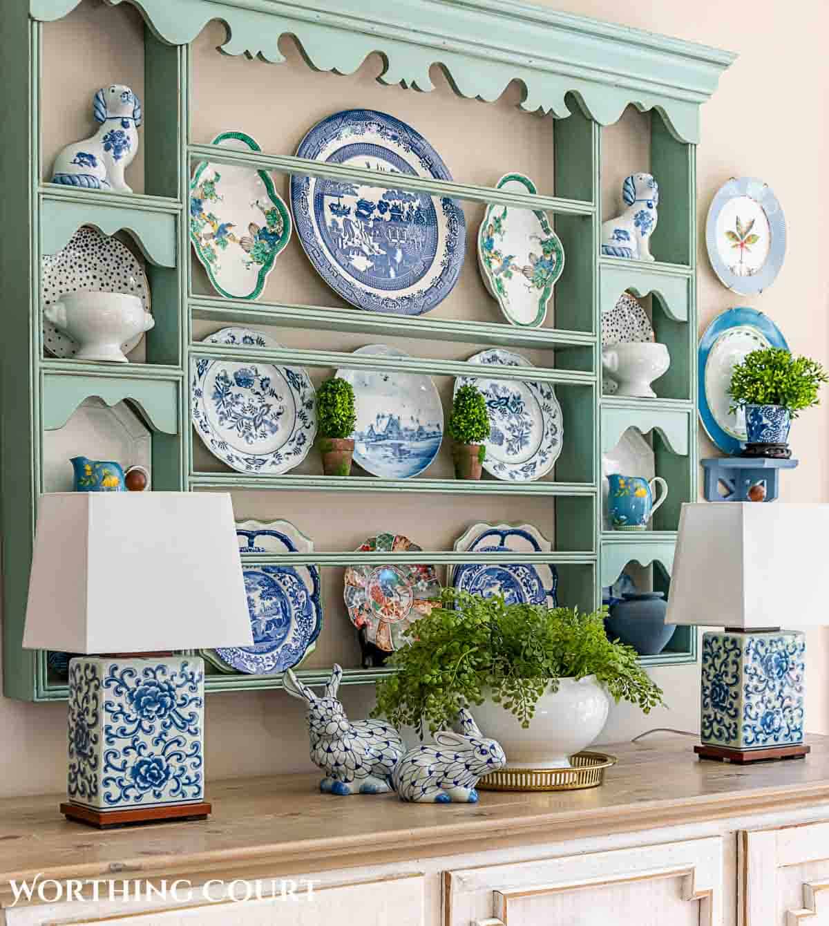 white sideboard with blue plate rack above filled with spring dishes and greenery