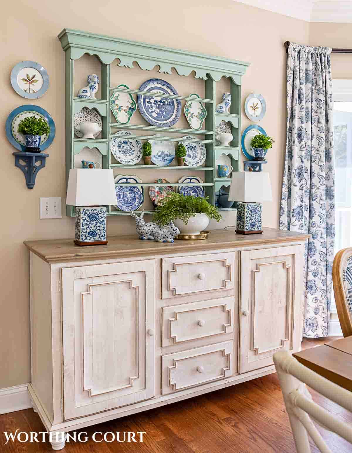 white sideboard with blue plate rack above filled with spring dishes and greenery