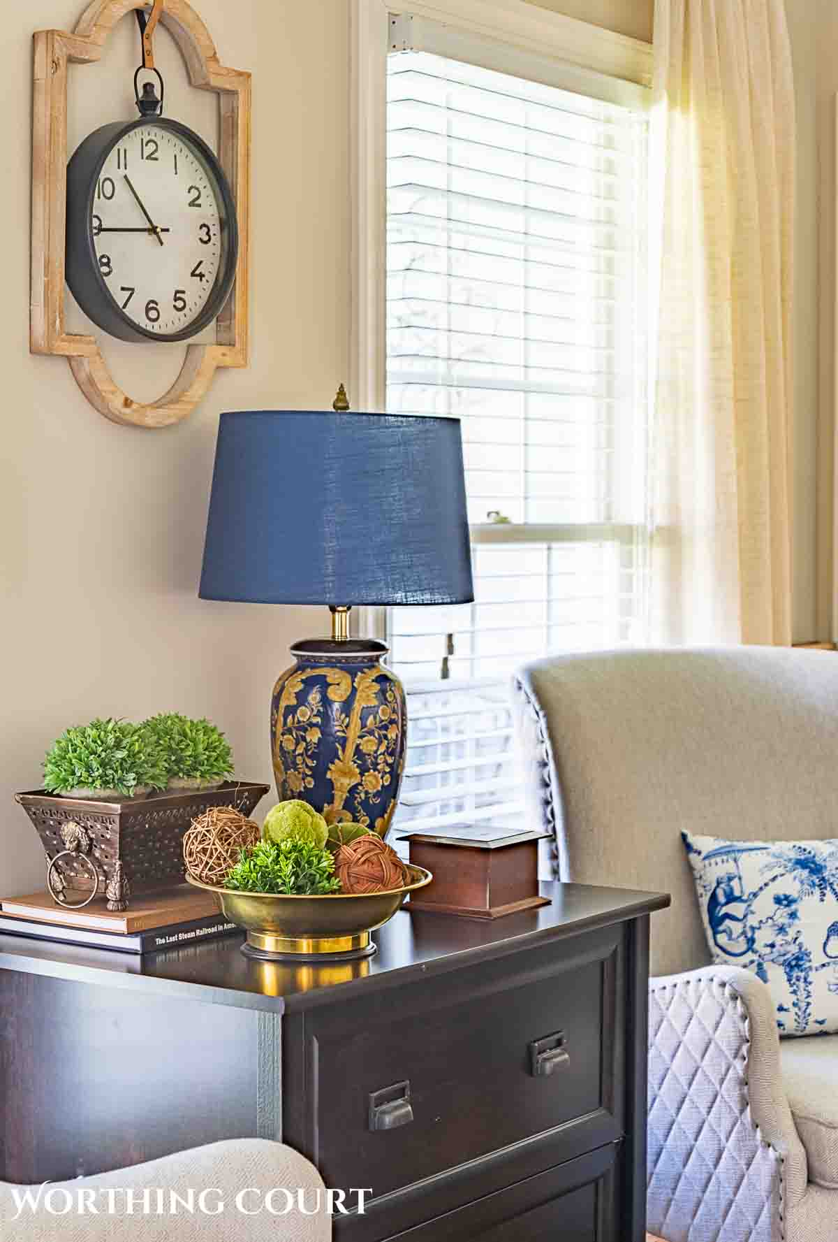 Spring decorations and greenery on a black chest in flanked by two gray chairs