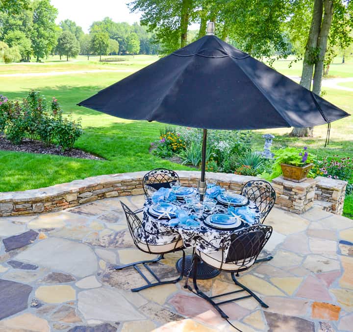 flagstone patio with an outdoor table and umbrella in a backyard