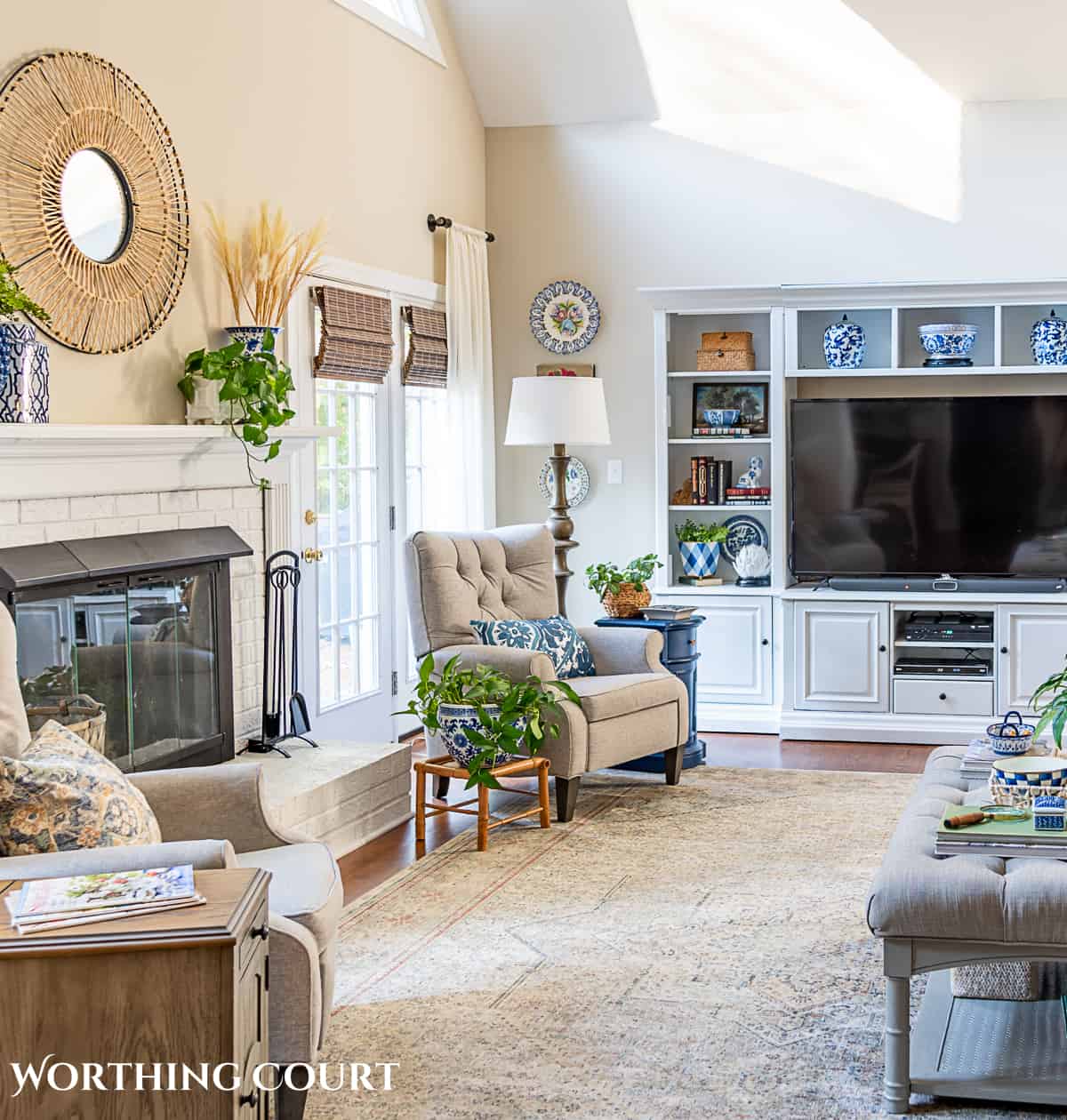 living room with mirror for wall art above fireplace, entertainment center and gray arm chairs