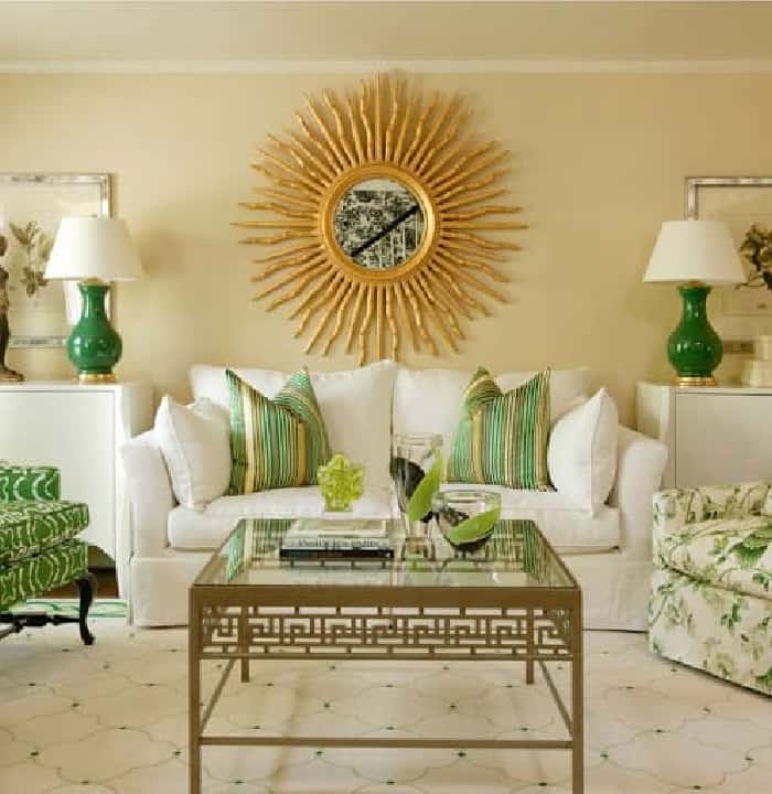 white sofa with large round gold mirror on wall above it