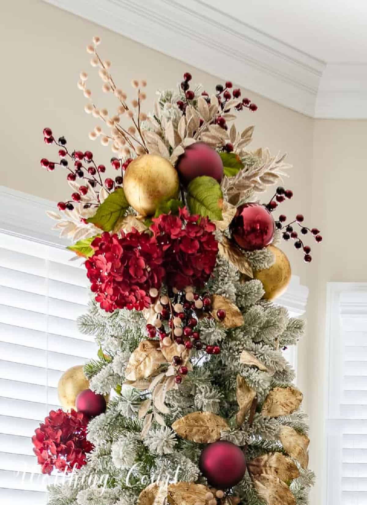 Christmas tree topper with gold ornaments and picks and burgundy hydrangeas