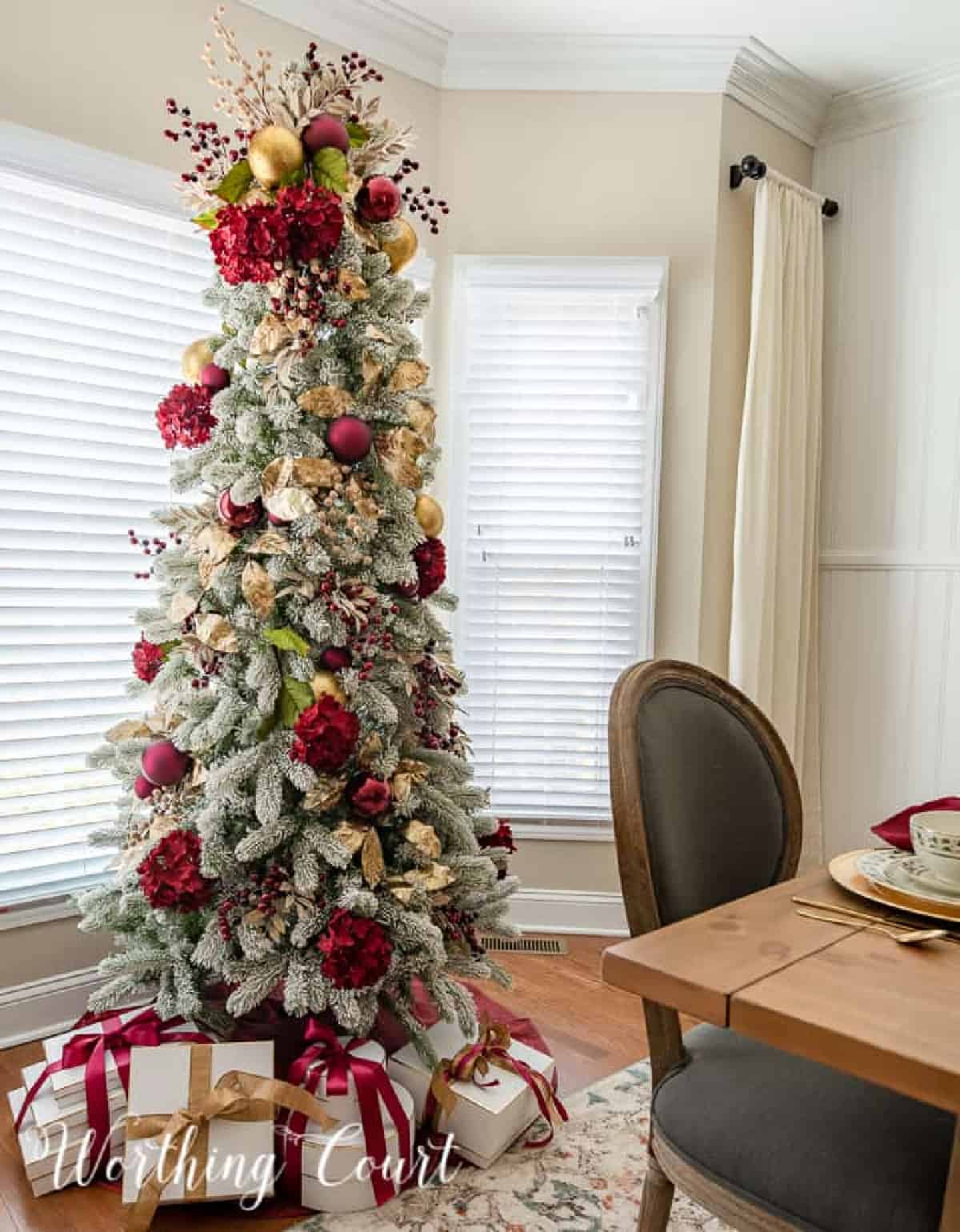 Flocked Christmas tree with gold ornaments and burgundy hydrangeas