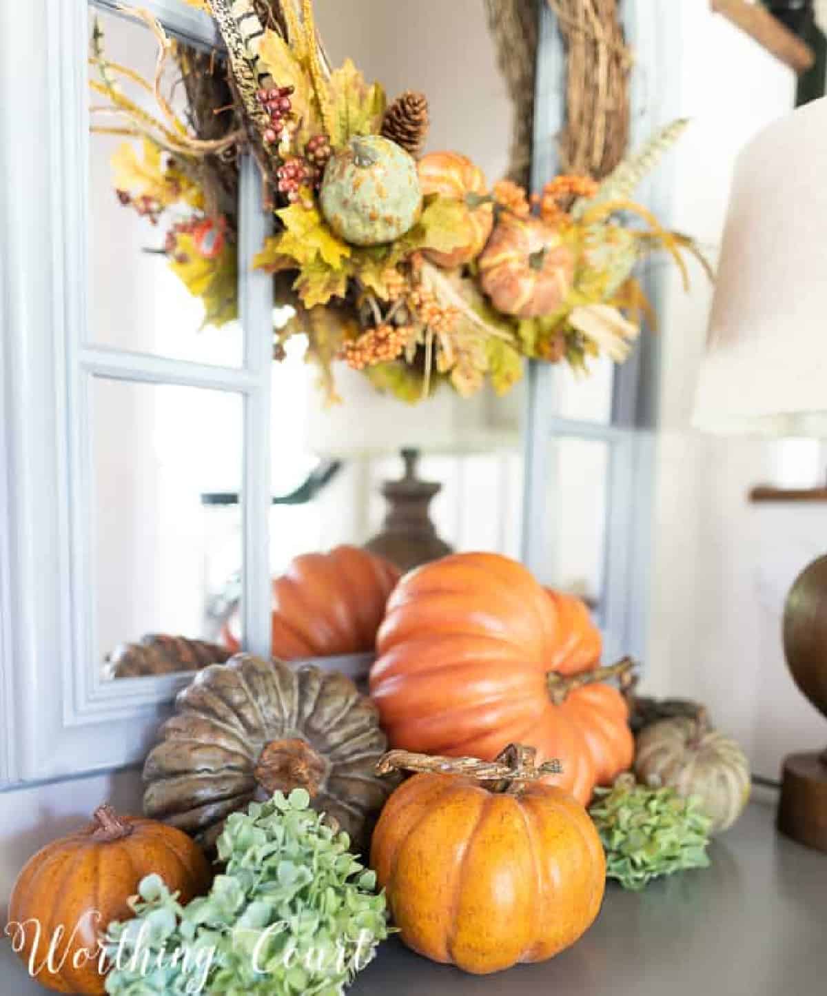 fall vignette with multiple pumpkins with blue hydrangeas tucked in