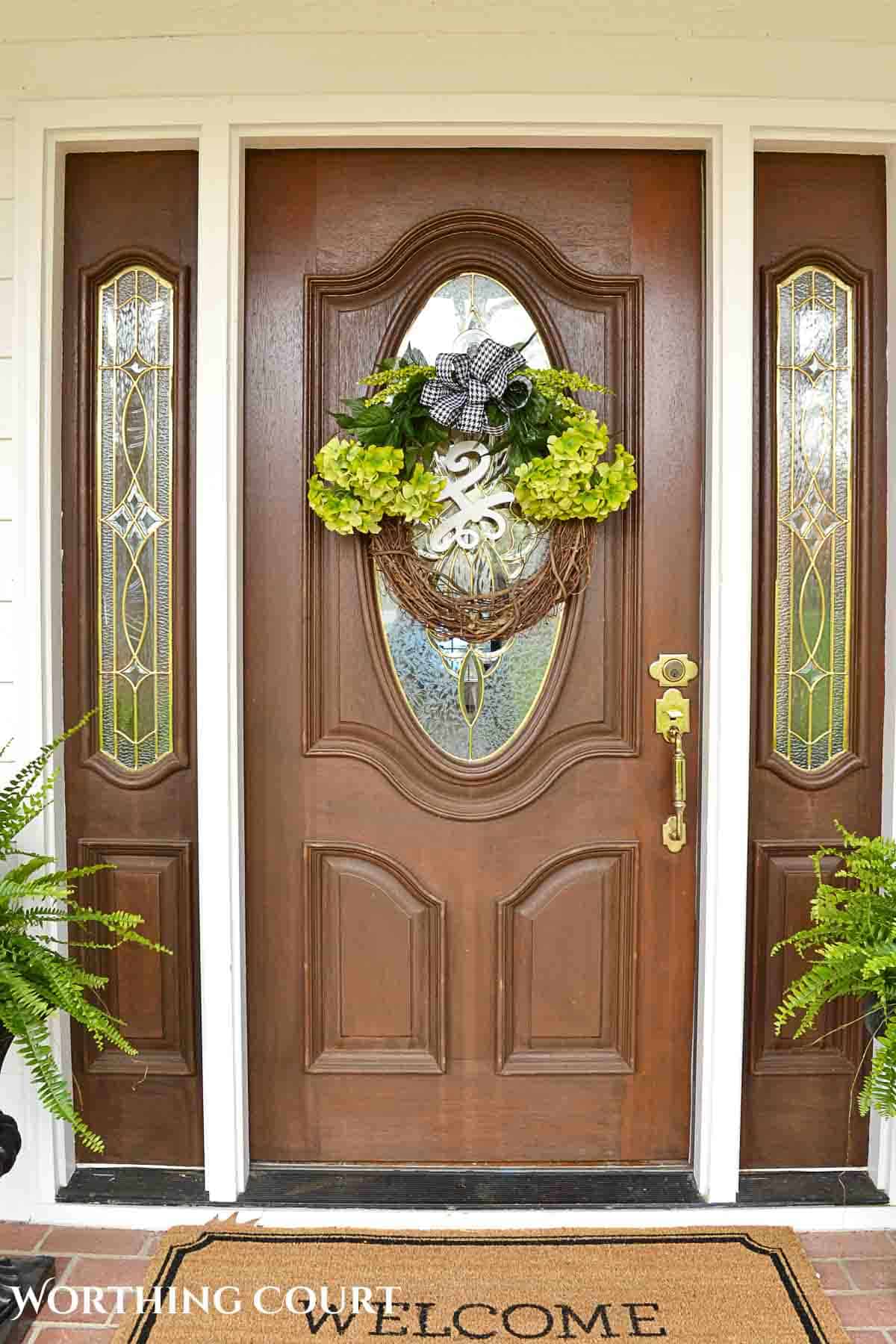 green hydrangea arrangement on a grapevine wreath hanging on a front door