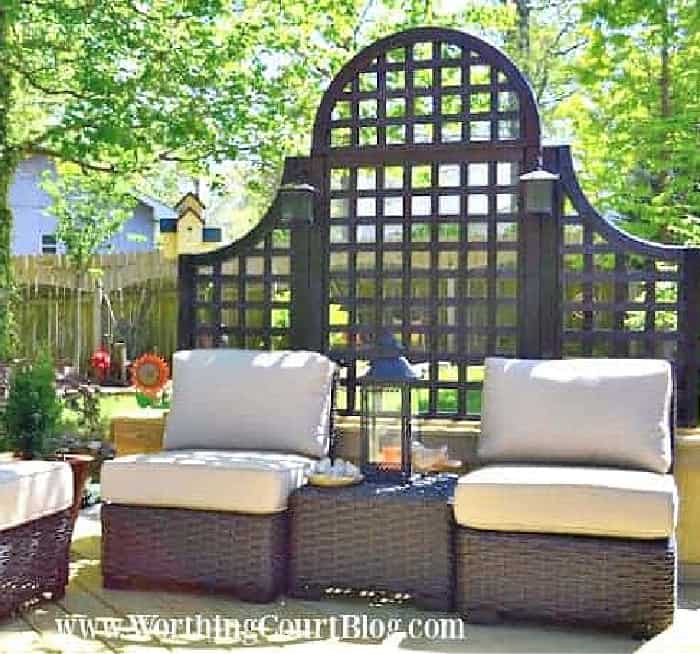 two outdoor chairs in front of an arched lattice background on a deck