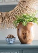 wood vase filled with greenery on a blue chest