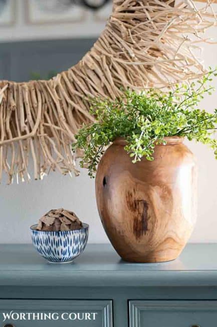wood vase filled with greenery on a blue chest