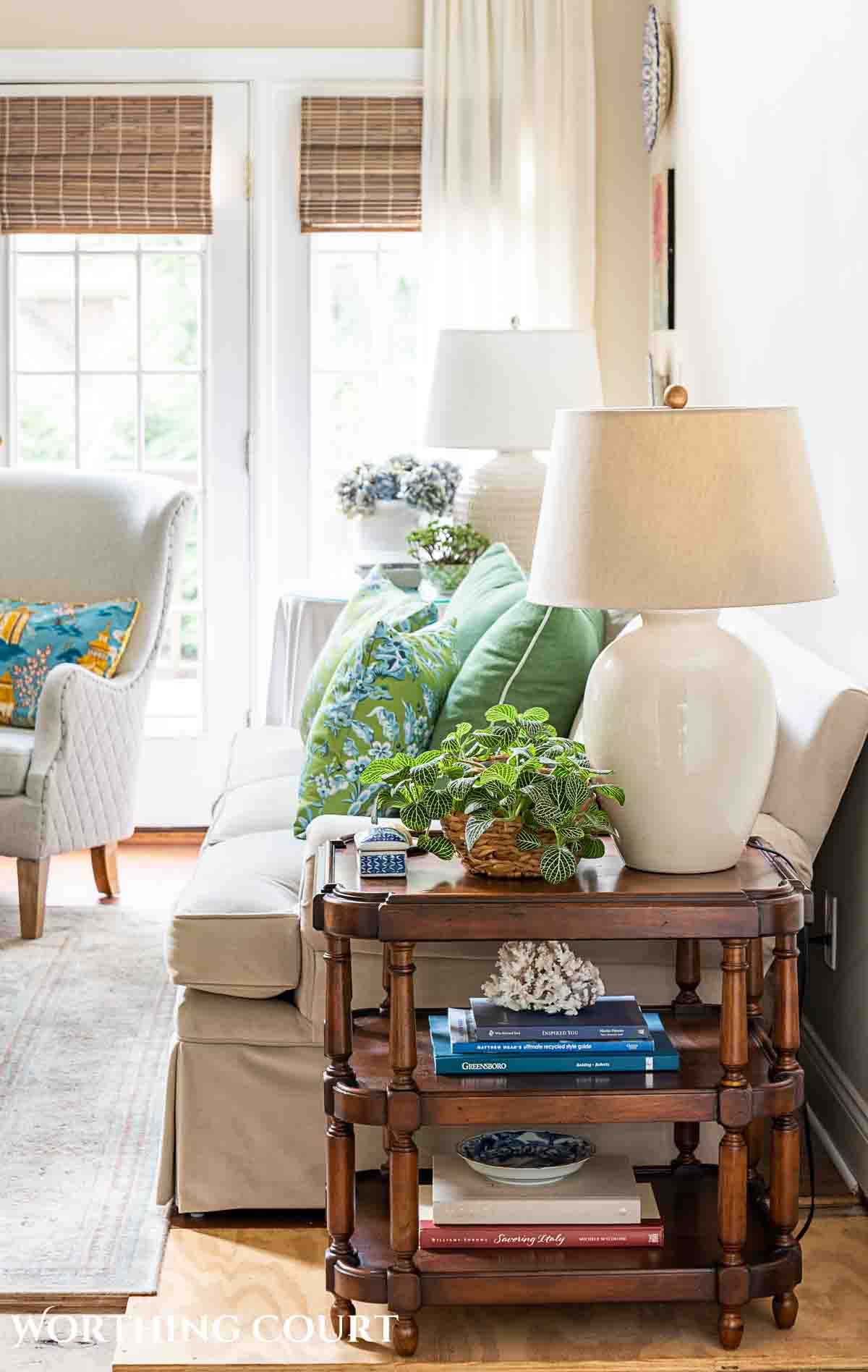 wood end table at the end of a beige couch with summer decorations