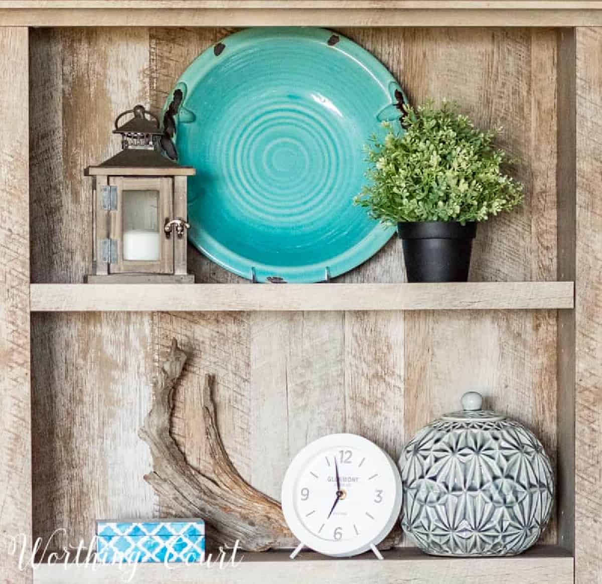 gray bookcase filled with coastal accessories