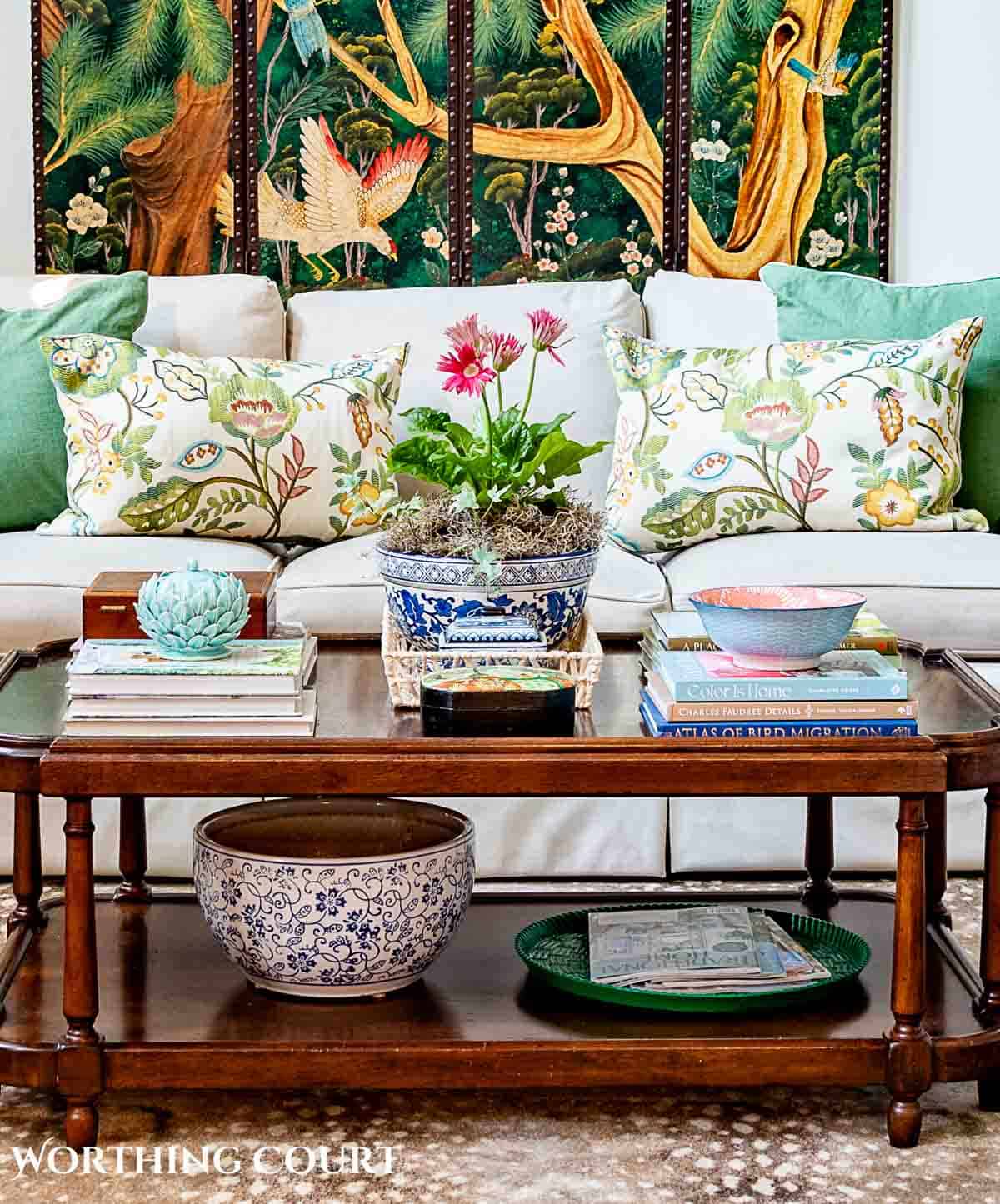 coffee table in front of tan couch with chinese screen on the wall and late summer chinoiserie accessories