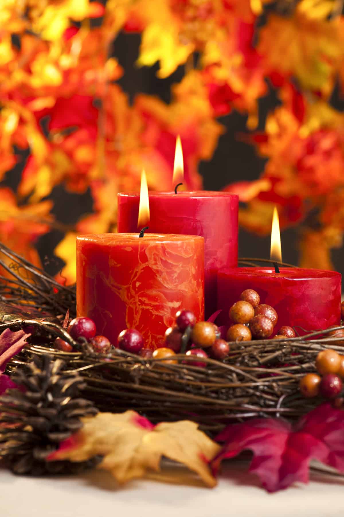 3 fall colored candles burning to demonstrate creating a fall aesthetic in your home with scent