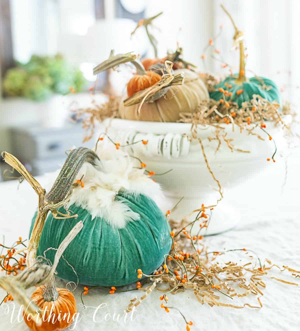 diy fall centerpiece with different colored velvet pumpkins in a large white footed bowl