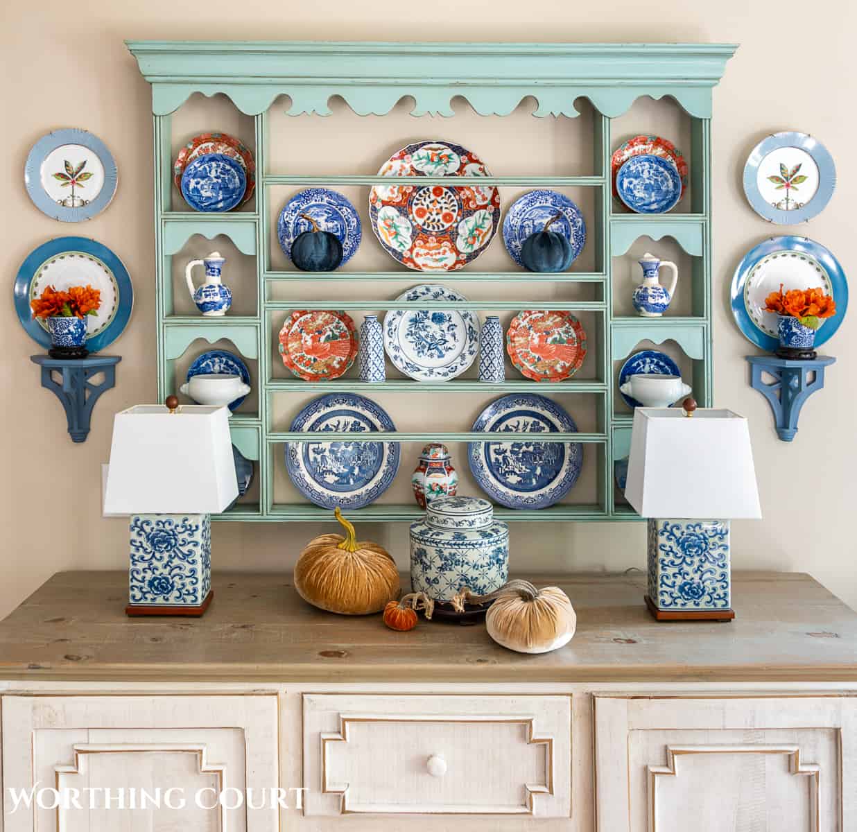 plate rack above a white sideboard filled with blue and white dishes and orange dishes for fall