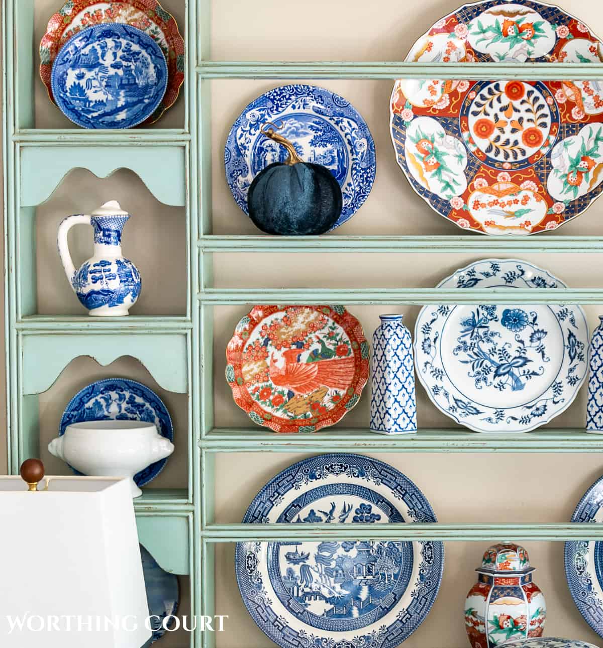 plate rack above a white sideboard filled with blue and white dishes and orange dishes for fall