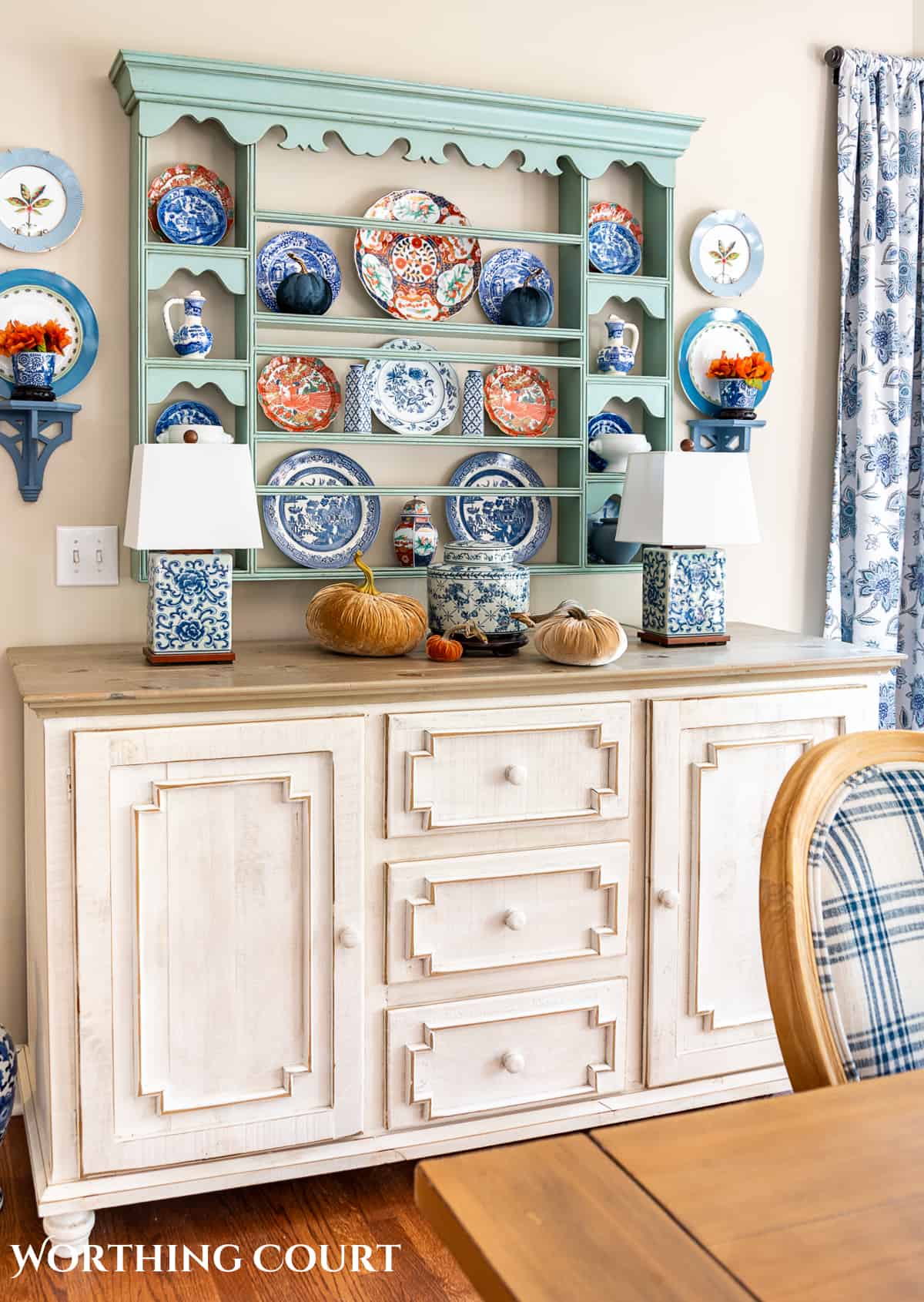 plate rack above a white sideboard filled with blue and white dishes and orange dishes for fall