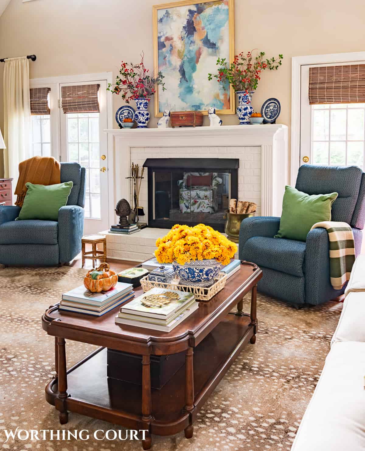 blue chairs flanking a white brick fireplace with fall decorations