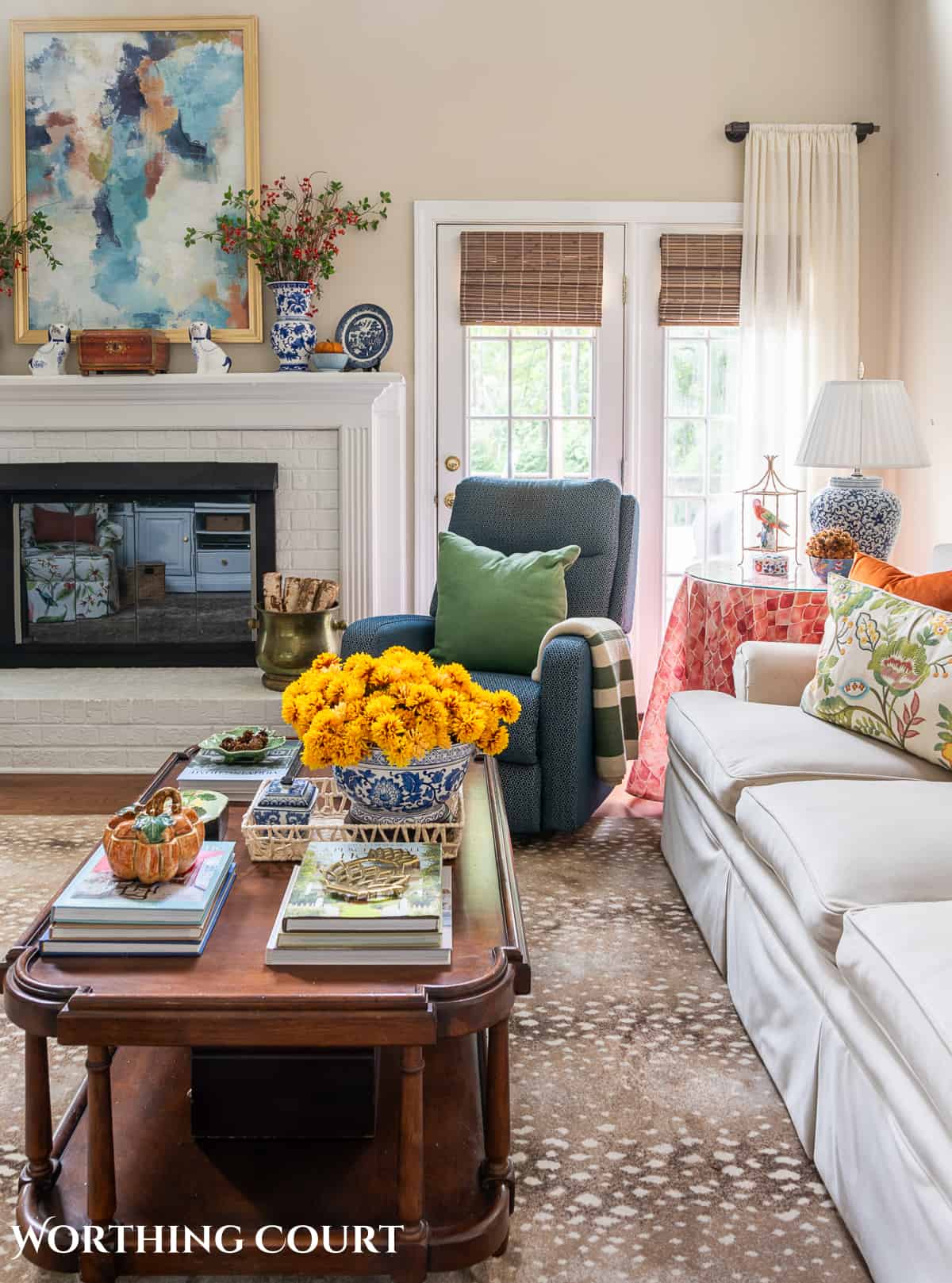 side view of beige sofa and blue chair beside white brick fireplace with fall decorations