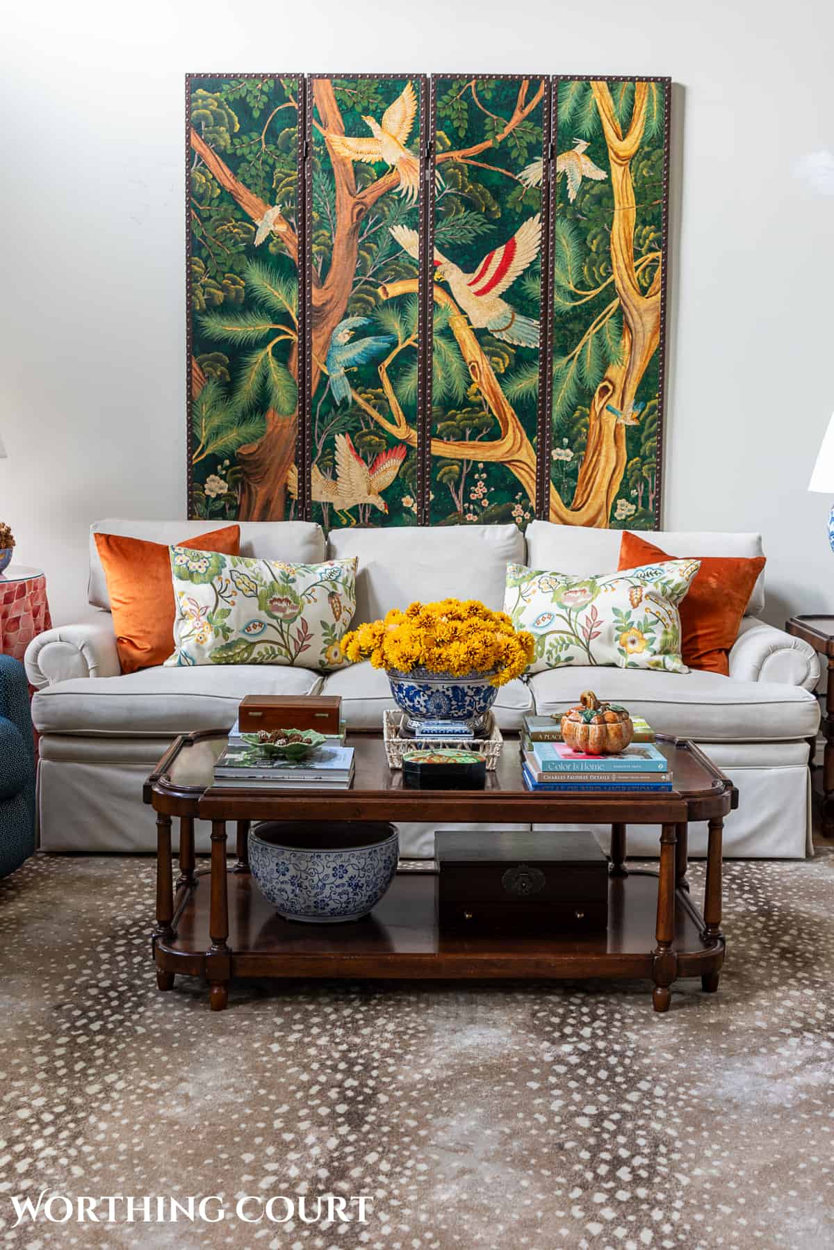 decorative wall screen hanging above a beige couch with fall throw pillows and a brown wood coffee table with fall decorations