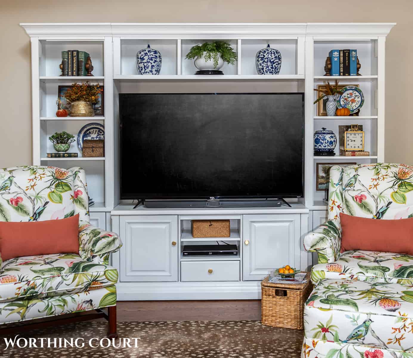 two floral upholstered arm chairs in front of a white media center with fall decorations