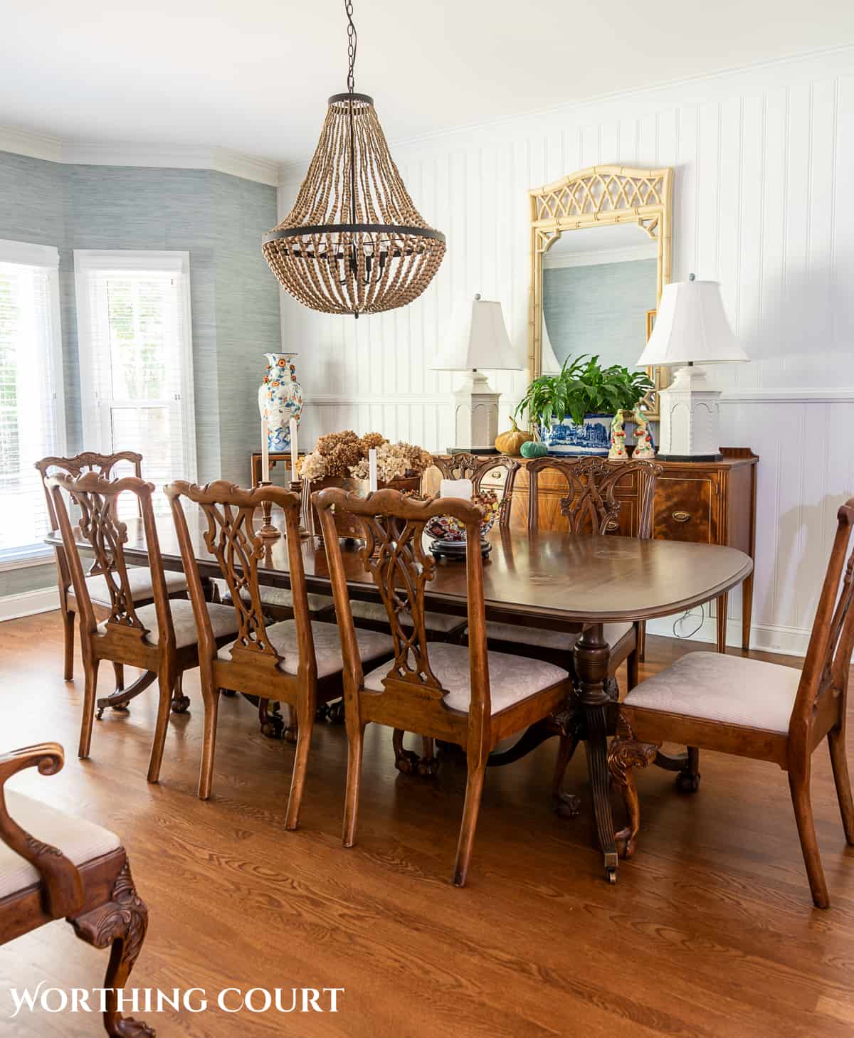 traditional dining table and chairs in a dining room with blue grasscloth wallpaper and fall decorations