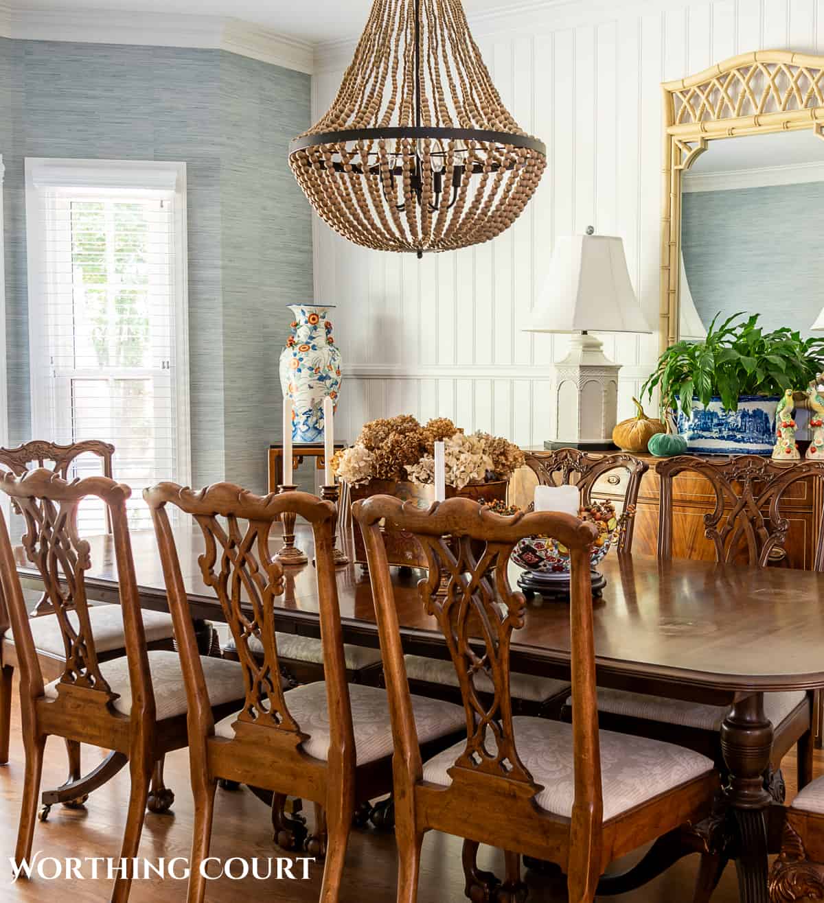 traditional dining table and chairs in a dining room with blue grasscloth wallpaper and fall decorations