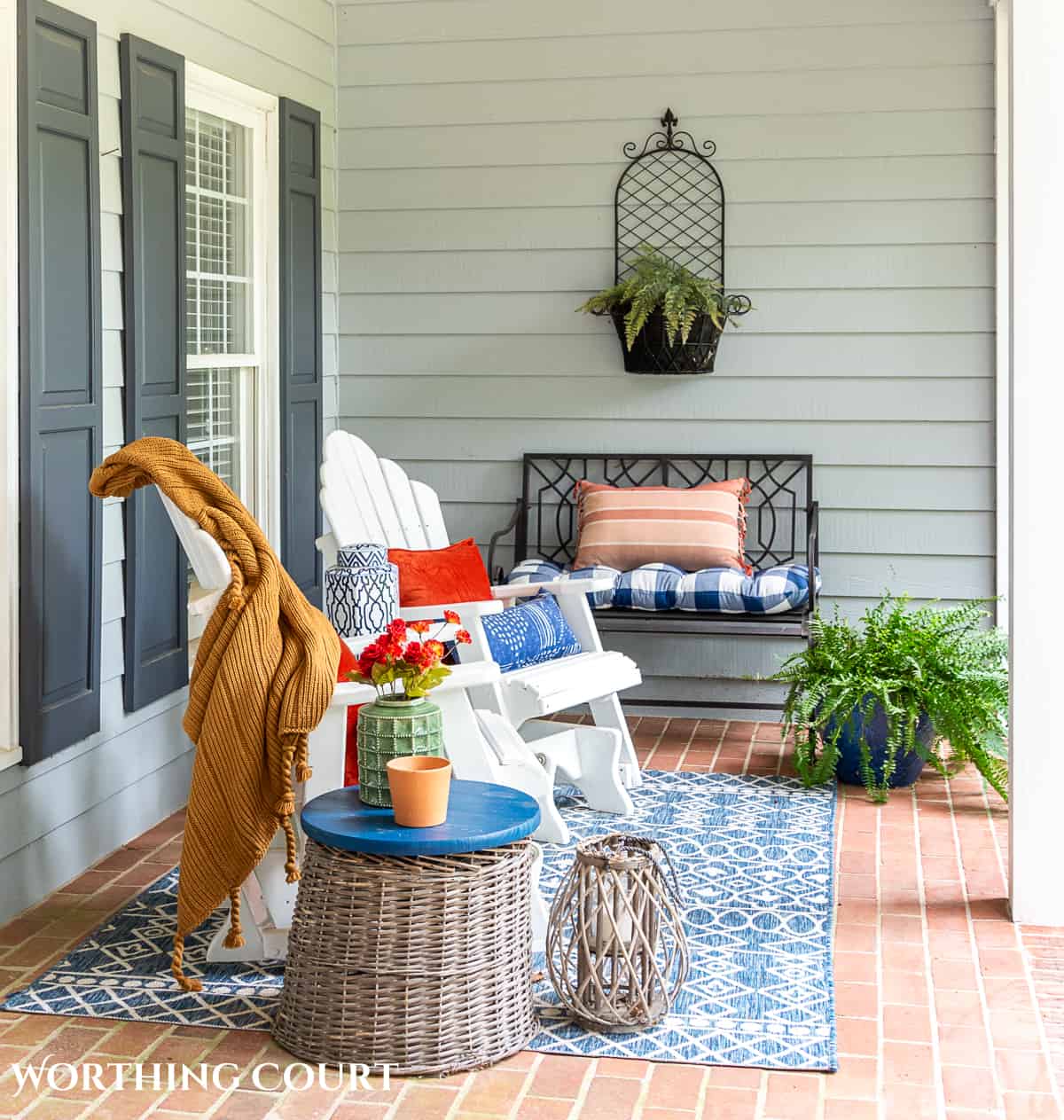 seating area on a large front porch decorated for fall with white gliders and other accessories