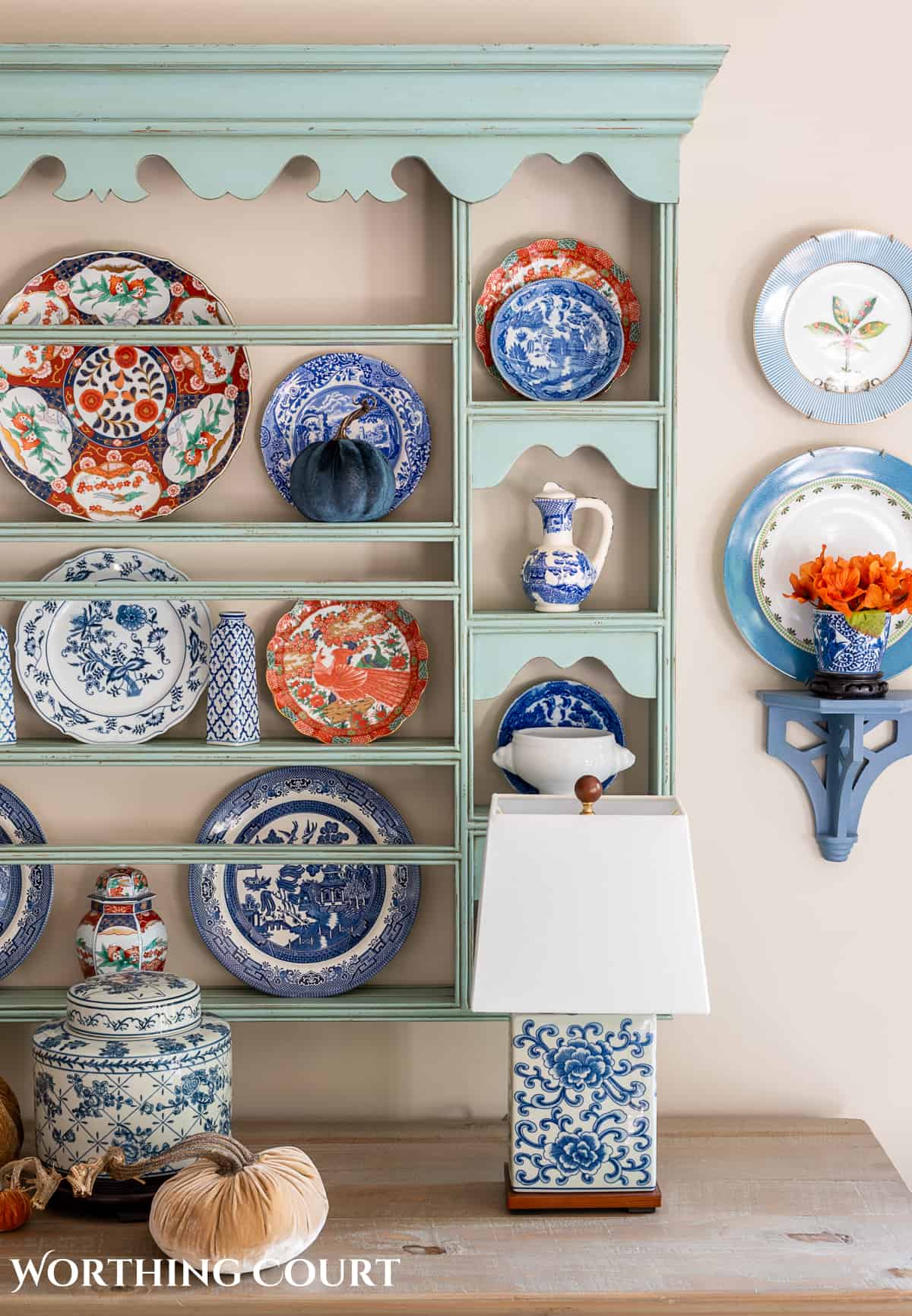 plate rack above a white sideboard filled with blue and white dishes and orange dishes for fall