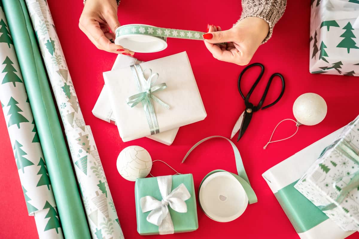 rolls of wrapping paper and ribbon on a table covered with a red cloth