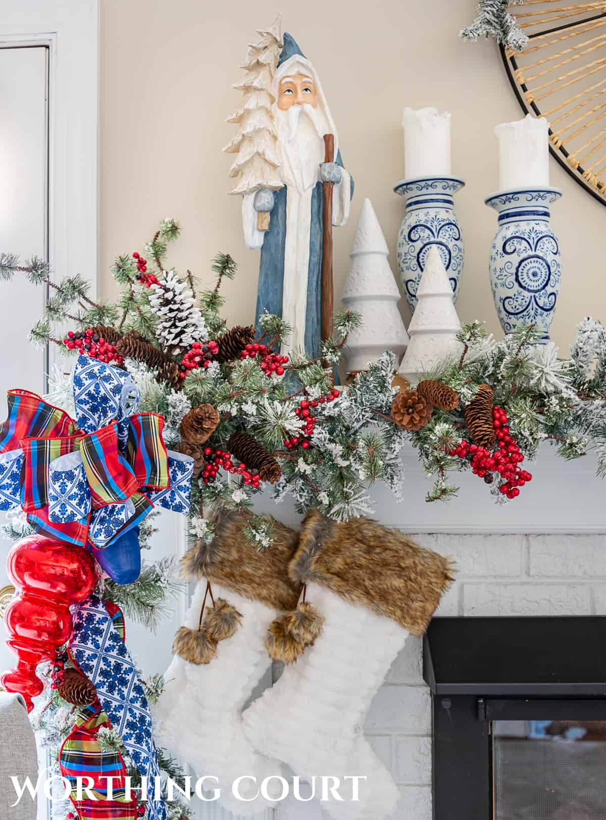 one end of a fireplace mantel with Christmas garland, ornaments and ribbon with a pair of fur topped stockings
