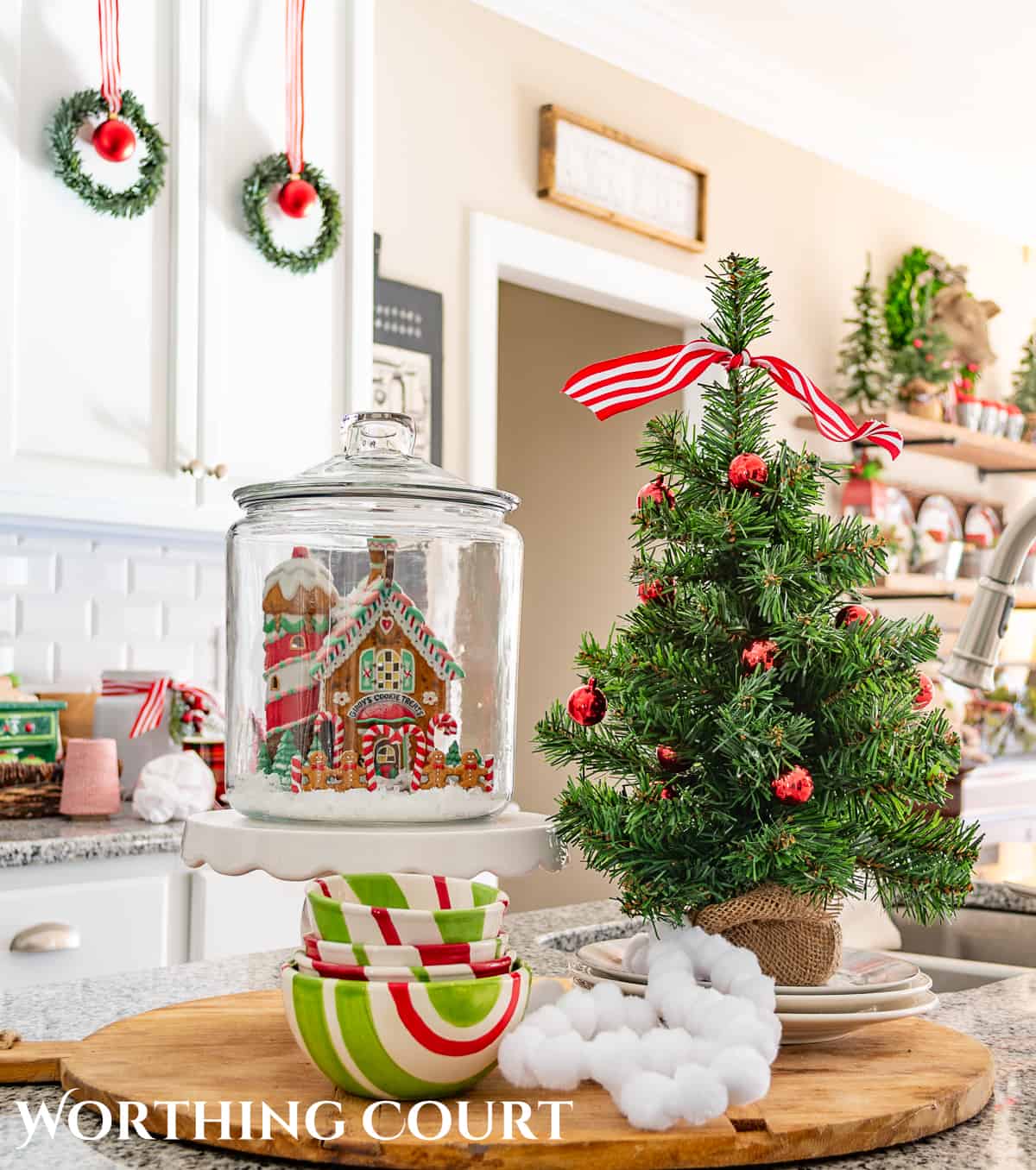 Christmas vignette on a kitchen island with a small tree and ceramic Christmas house.