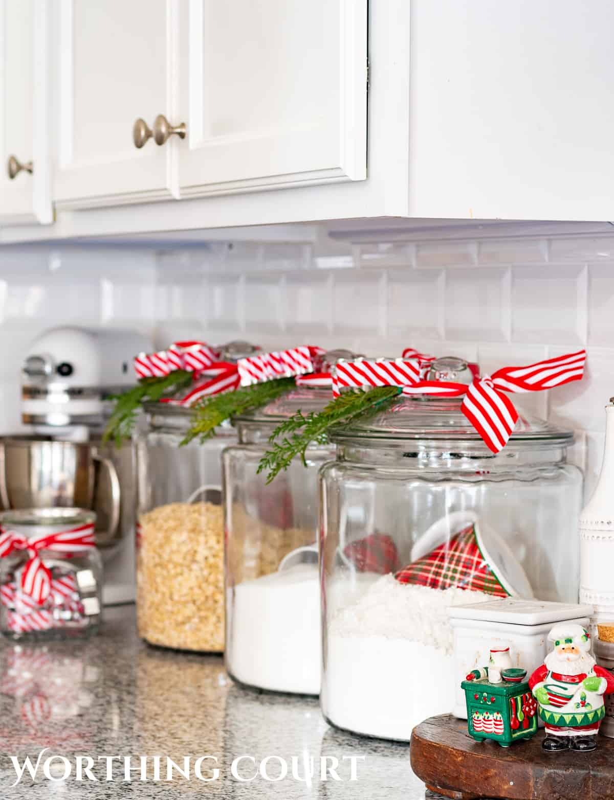 clear glass canisters with red and white striped ribbon an greenery bits tied to the tops