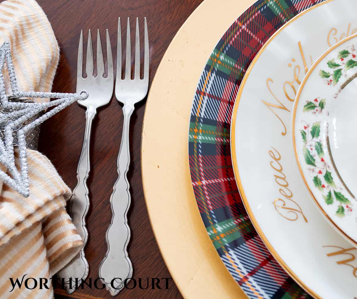 Christmas place setting with Christmas china plates stacked with tartan plaid plates on a gold charger