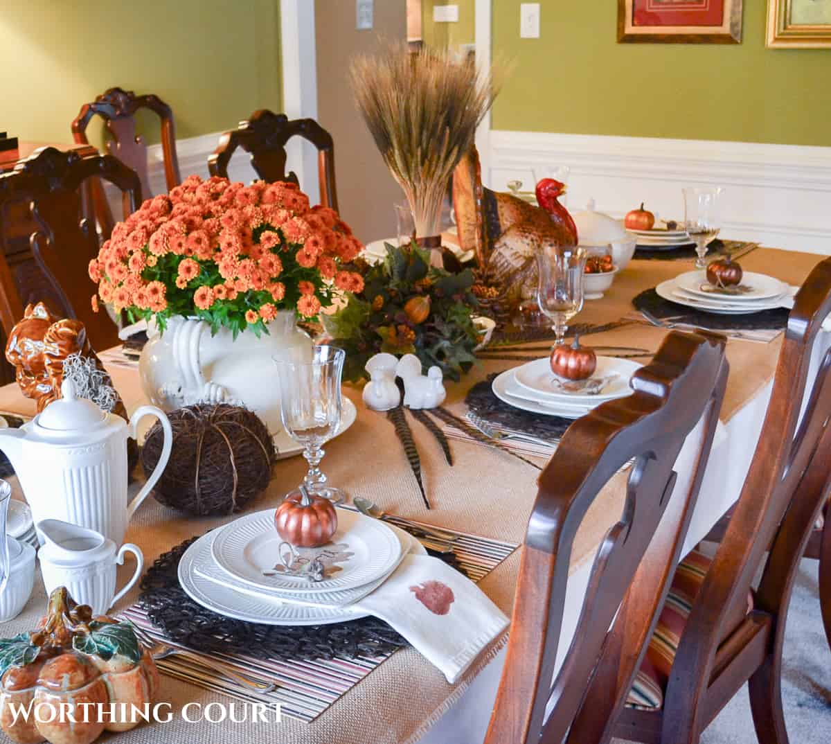 Woodland themed Thanksgiving table setting with fall colored mums, a cornucopia, ceramic squirrel and white dishes