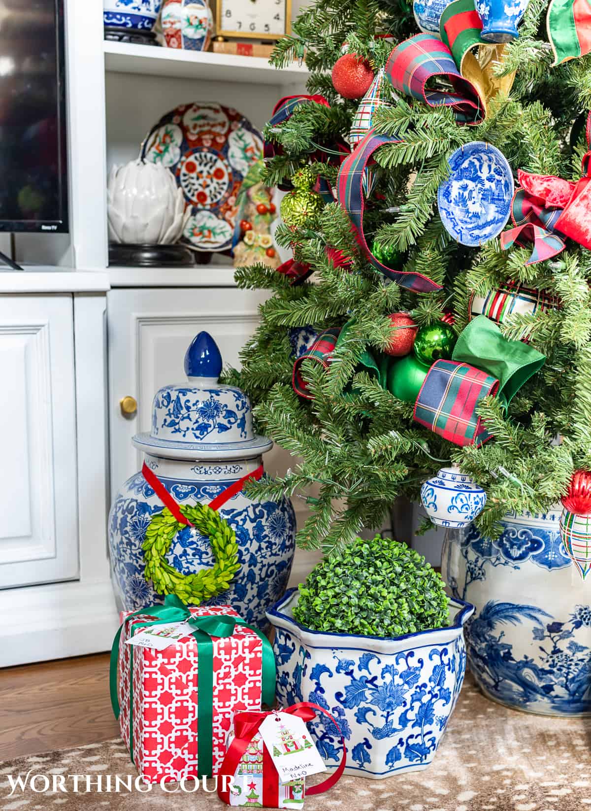 gifts at base of Christmas tree with traditional decorations and presents wrapped in colorful Christmas wrapping paper