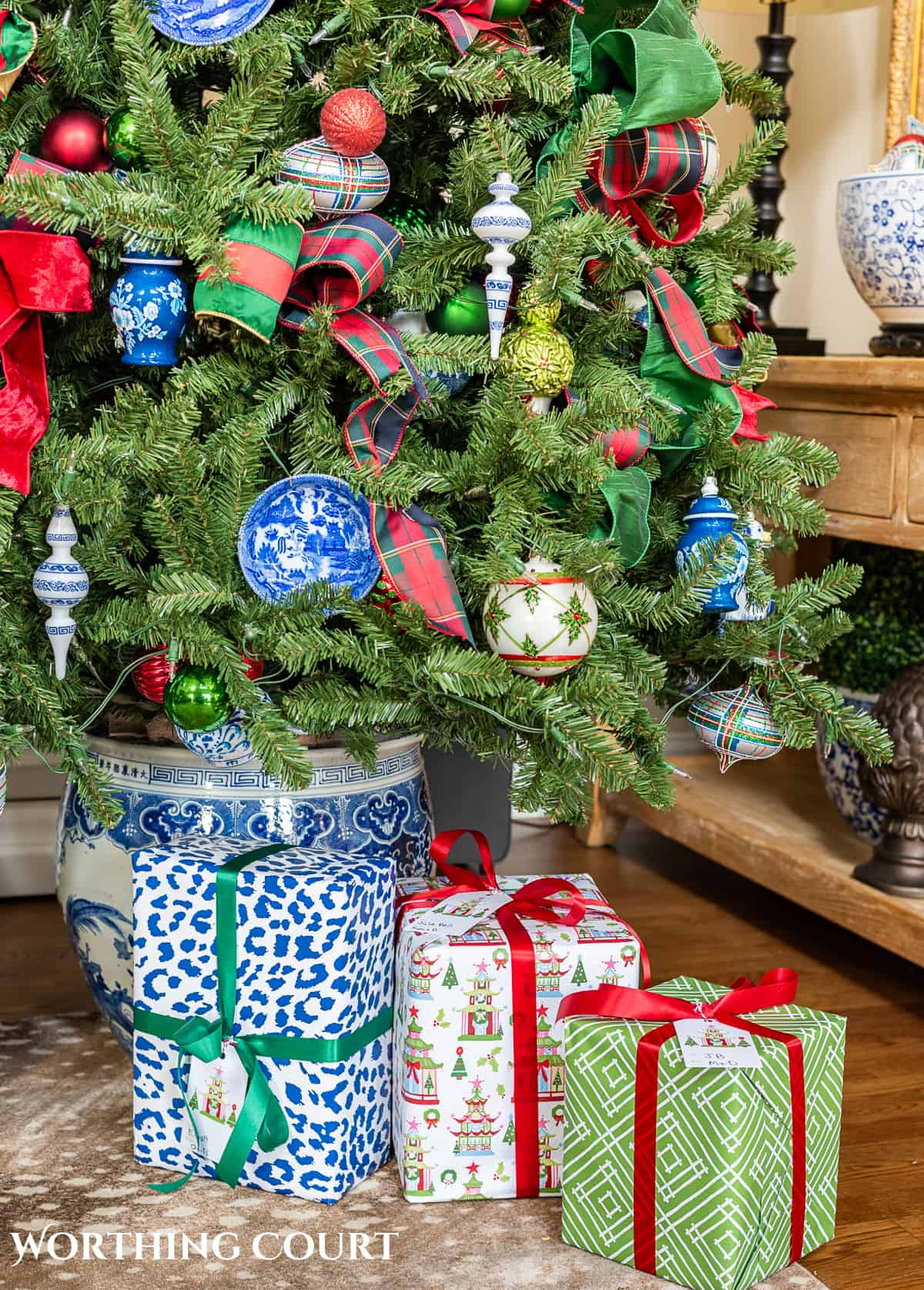 gifts at base of Christmas tree with traditional decorations and presents wrapped in colorful Christmas wrapping paper