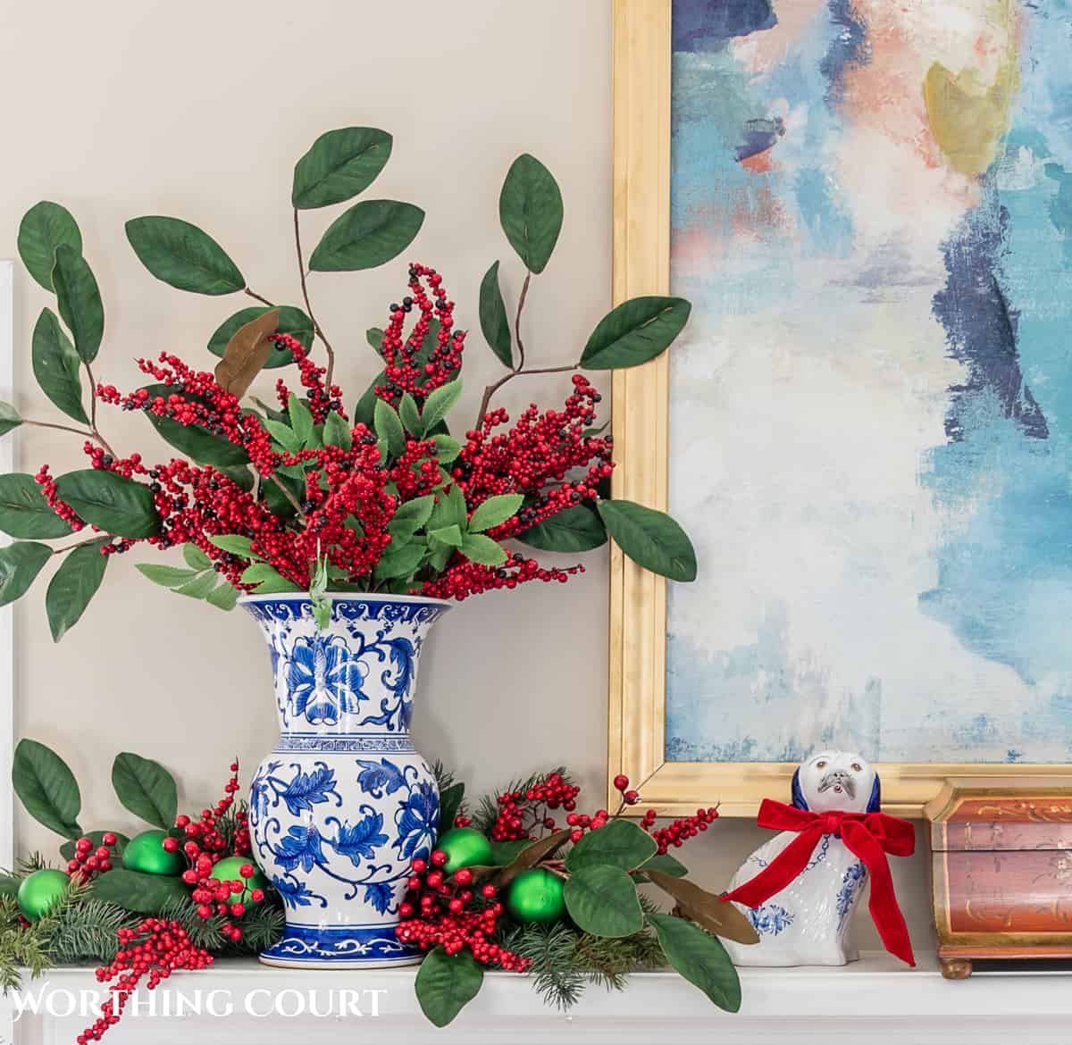 fireplace mantel with abstract art above and traditional Christmas decorations mixed with chinoiserie decor items