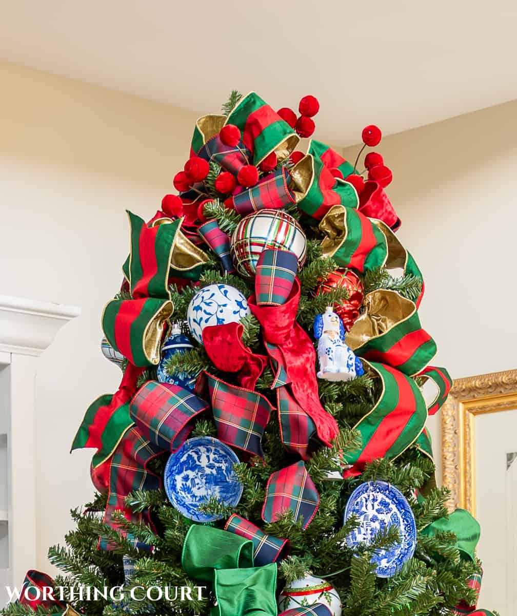 Top of Christmas tree with green and red ribbon, red ball picks and blue and white ornaments